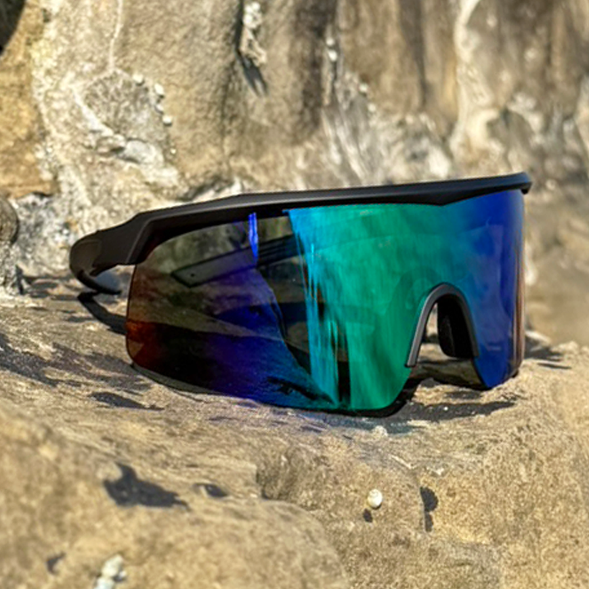 E3 Optics E3-A3 green mirror polarized sunglasses with matte black frame – ideal for cycling, running, and active outdoor sports – angled side view on rocky outdoor surface.