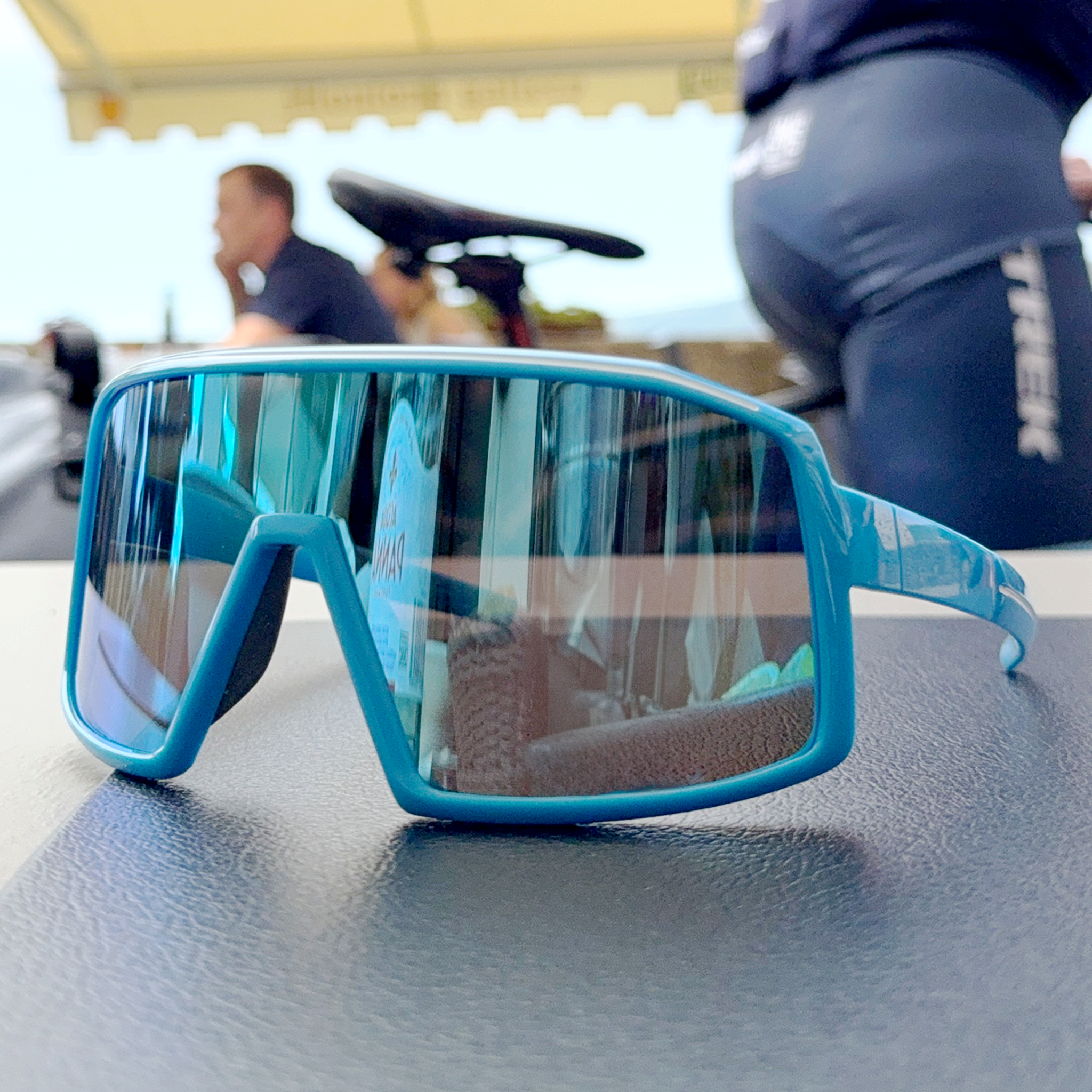 E3 Optics E11 precise lens sunglasses on table with bike helmet – cycling eyewear with impact resistant lenses.