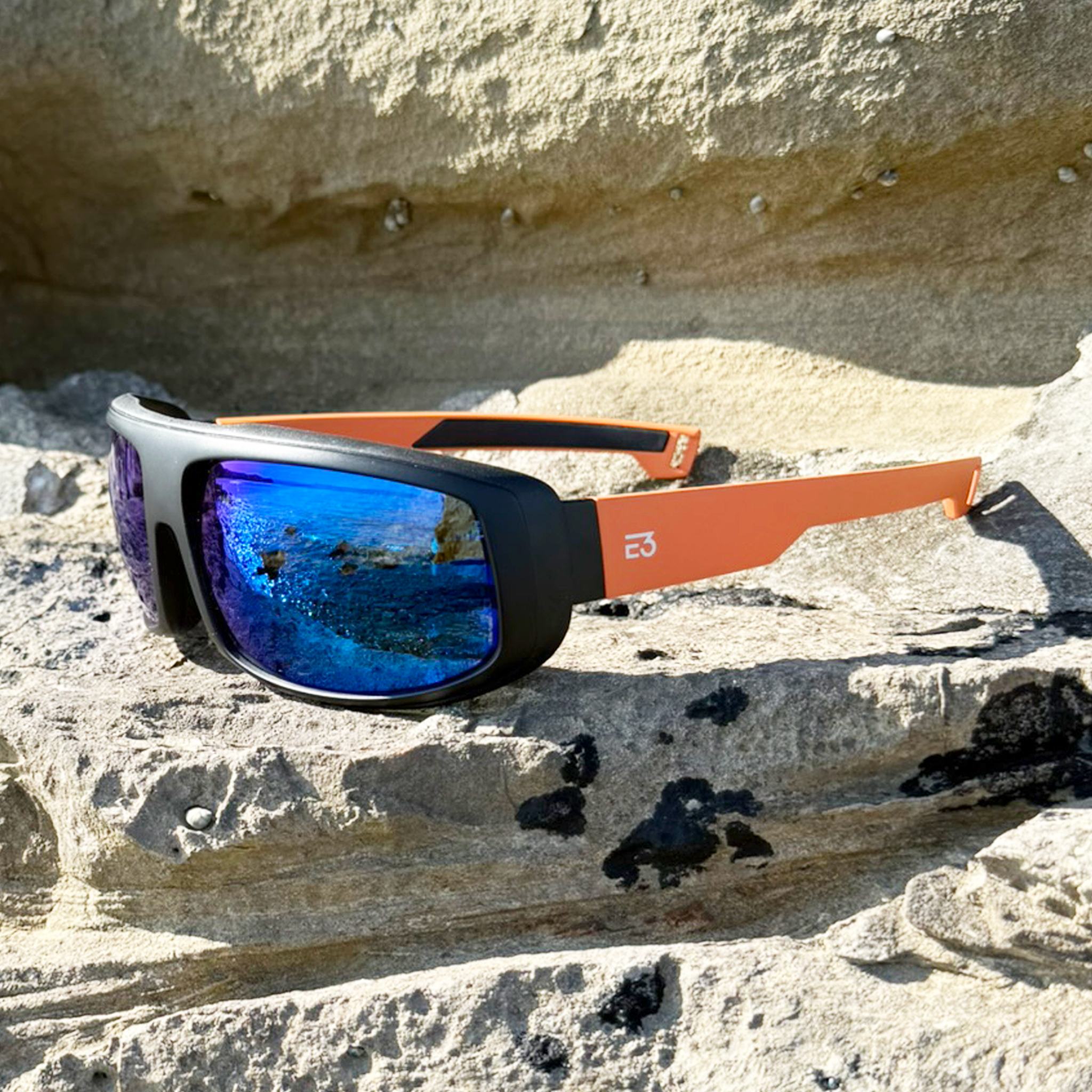 E3 Optics E15 polarized sunglasses on rock by mountainside – high-performance outdoor eyewear.