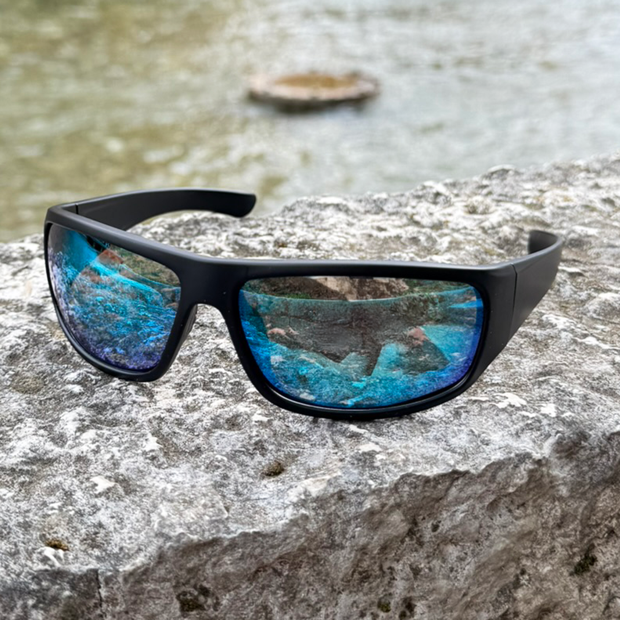 E3 Optics E16 polarized floating sunglasses on rock by riverside, designed for boating and kayaking.