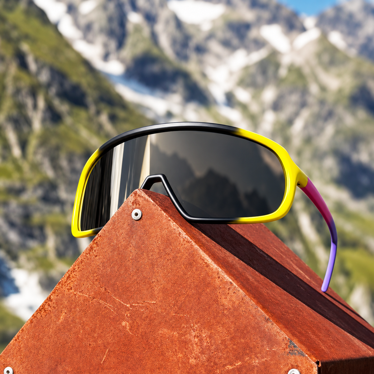 Sport sunglasses with a yellow-to-purple gradient frame and dark lenses, resting on a rusted metal structure with a blurred mountain background.