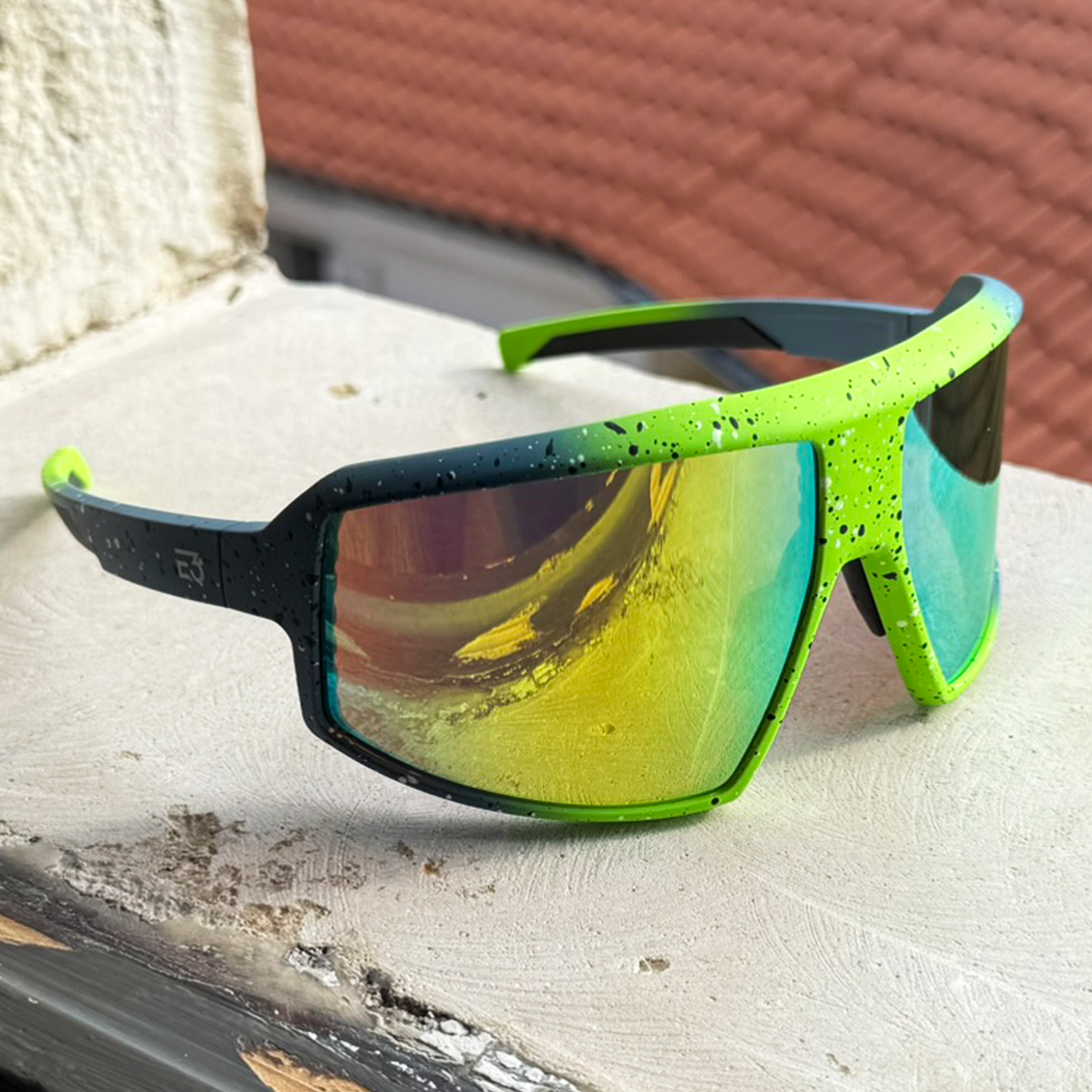E3 Optics E9 precise lens sunglasses with reflective green-blue mirror lenses photographed at a window.